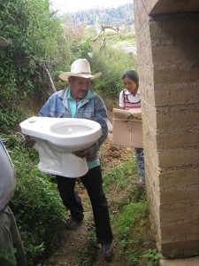 Mixteco family from Mini Numa, Guerrero carrying their new toilet to an adobe bathroom for installation; photo by Daniel Moss