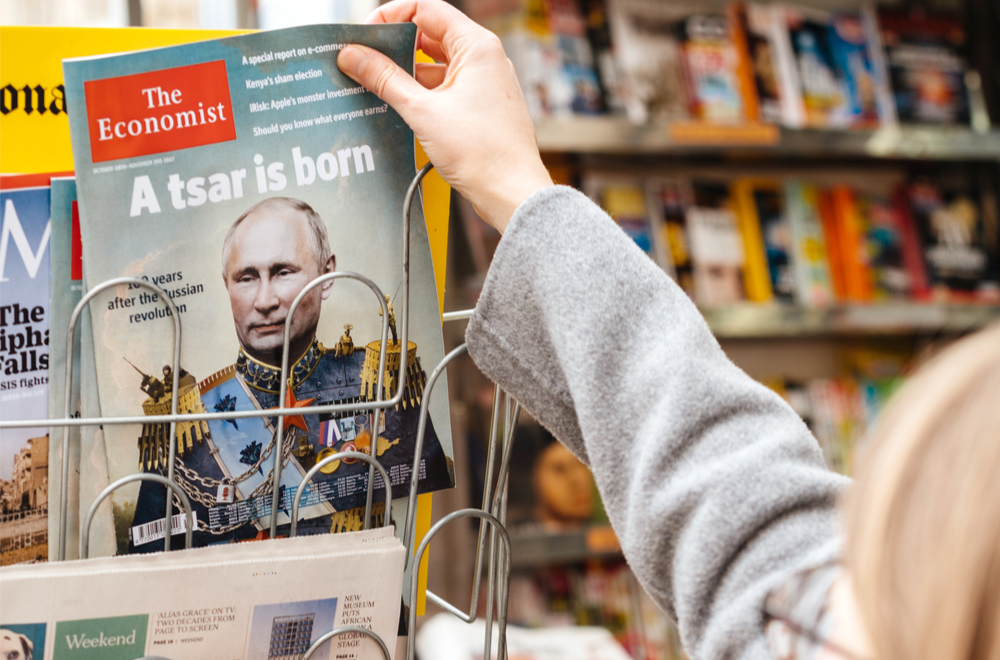 A woman reaches for a magazine with Putin styled as a tsar on the cover. (Shutterstock)