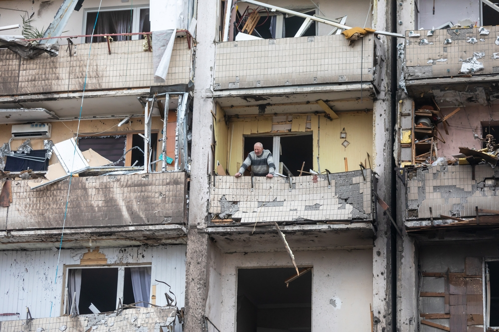 A Ukrainian man contemplates the wreckage of Russian missile attacks from the balcony of a badly damaged apartment building in Kyiv. (Shutterstock)