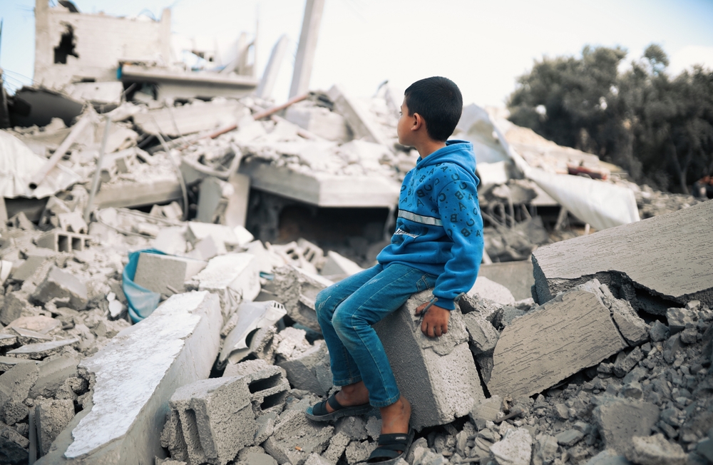 A boy sits among the rubble following an Israeli airstrike on Gaza, March 2023. (Shutterstock)